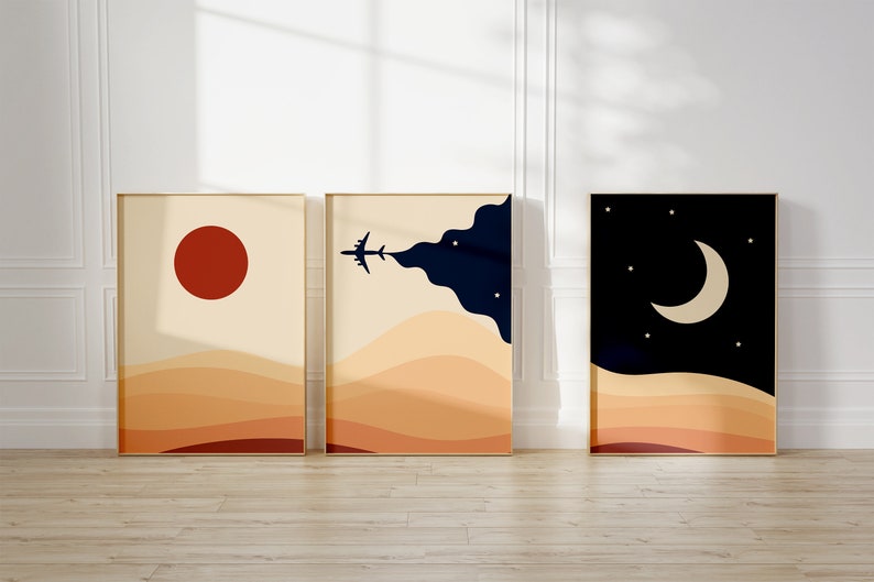 Set of three minimalist desert posters featuring abstract sand dunes, red sun, airplane in the sky, and moon with stars. Modern boho wall art in warm beige and navy tones.