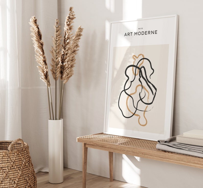 May include: A framed print with the text "ART MODERNE" and a minimalist abstract design featuring black and beige lines on a beige background.