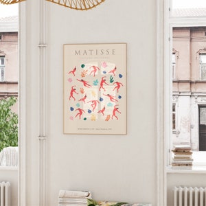 Puede incluir: Un p&oacute;ster con un dise&ntilde;o minimalista que presenta una pintura de Henri Matisse titulada "El Caracol". El p&oacute;ster es de color crema con un marco marr&oacute;n claro. La pintura representa una ventana con figuras rojas bailando en su interior. El texto "MATISSE" est&aacute; en la parte superior del p&oacute;ster, y el texto "LE  SNAIL  (THE  SNAIL) - Henri Matisse, 1953" est&aacute; en la parte inferior.