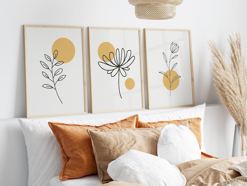 May include: Three framed prints with minimalist line drawings of flowers and leaves on a white background. Each print features a yellow circle.