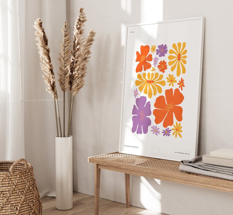 K&ouml;nnte beinhalten: Ein wei&szlig;er gerahmter Druck mit einem farbenfrohen Blumendesign. Der Druck zeigt orange, gelbe und lila Blumen auf wei&szlig;em Hintergrund. Der Text "Art Gallery, Paris" befindet sich am unteren Rand des Drucks.