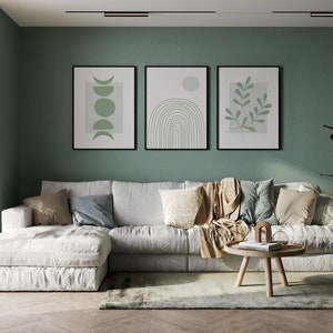 Pu&ograve; includere: Un divano angolare bianco con una coperta di lana marrone e cuscini in un soggiorno con una parete verde e tre stampe incorniciate di arte astratta. La stanza ha un pavimento in legno e un piccolo tavolino da caff&egrave; in legno.