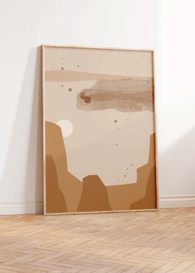 May include: A framed abstract print with a beige background and brown shapes. The print features a large brown cloud shape in the center and smaller brown circles scattered throughout. The print is framed in a light wood frame.