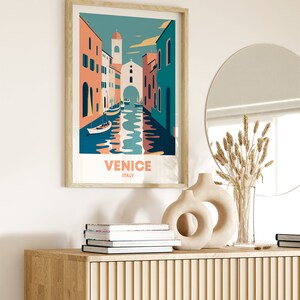 May include: A framed illustration of a canal in Venice, Italy. The illustration features colorful buildings, boats, and a blue sky. The text "VENICE ITALY" is printed below the illustration.
