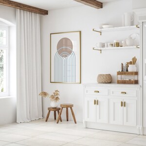 May include: A white kitchen cabinet with two drawers and four doors. The cabinet has gold hardware and a white marble countertop. There are two shelves above the cabinet with gold brackets. The shelves are decorated with a wicker basket, a vase with dried flowers, and other decorative items.
