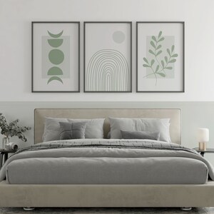 Pu&ograve; includere: Un letto imbottito grigio con un piumone grigio e due cuscini. Tre stampe incorniciate con disegni verdi astratti sono appese sopra il letto.