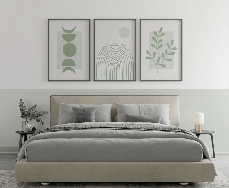 Pu&ograve; includere: Un letto imbottito grigio con un piumone grigio e due cuscini. Tre stampe incorniciate con disegni verdi astratti sono appese sopra il letto.