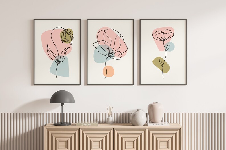 May include: Three framed prints with abstract line drawings of flowers in black on a white background. Each print features a different flower with pink, blue, and green abstract shapes.