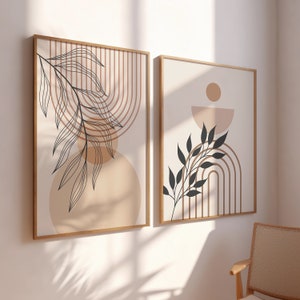Peut inclure: Deux impressions encadrées avec des motifs abstraits présentant des formes géométriques brunes et beiges et des silhouettes de feuilles noires. Les impressions ont une esthétique minimaliste.