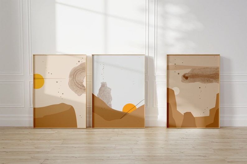 May include: Three abstract art prints in gold frames with a beige background and brown and yellow geometric shapes. The prints have a minimalist style.