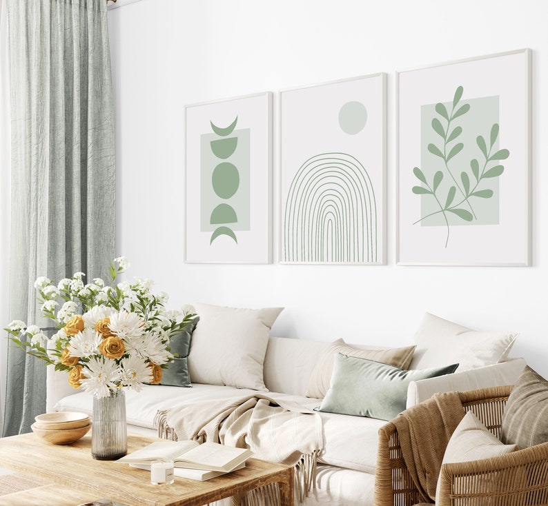 Pu&ograve; includere: Tre stampe d'arte minimaliste con sfondo bianco e disegni astratti verdi. Le stampe presentano un design a mezzaluna e cerchio, un arcobaleno e un ramo frondoso.