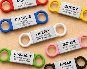 May include: Seven rectangular pet ID tags with silicone frames in red, yellow, blue, white, pink, green, and black. Each tag features a central metal plate engraved with a pet name and contact information, including phone numbers and addresses.