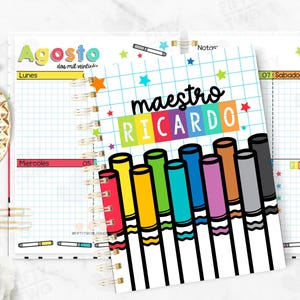May include: A spiral-bound planner with a colorful cover featuring the text "maestro RICARDO" and illustrations of markers. The planner is open to a page with grid lines and the month of August.