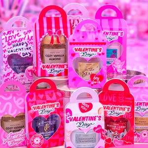 Puede incluir: Una colección de bolsas de regalo rosas de San Valentín con recortes de corazón, cada una con un frasco pequeño. Las bolsas presentan textos como "Valentine's Day" y nombres de productos. La imagen también incluye texto sobre los soportes PocketBac.