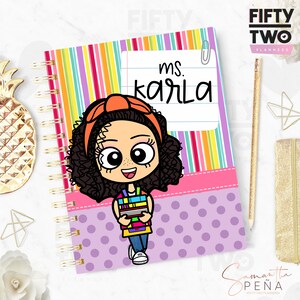 May include: Spiral-bound notebook with a colorful striped cover and a cartoon illustration of a person holding books. The notebook features the text "ms. Karla" on a lined paper design. The notebook has a pink band with purple polka dots.