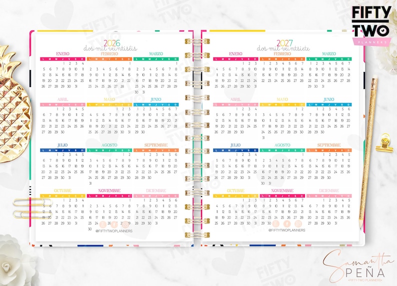 May include: A spiral-bound planner open to show 2026 and 2027 calendars with colorful monthly headers. The pages feature grid layouts for each month, the text FIFTY TWO PLANNERS, and the social media handle @FIFTYTWOPLANNERS printed at the bottom.