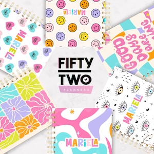 Puede incluir: Una colección de cuadernos con espiral con cubiertas coloridas y estampadas. Los diseños incluyen caras sonrientes, corazones, flores y motivos de ojos. El nombre "Mariela" aparece en varios cuadernos. El logotipo de Fifty Two Planners está en el centro.