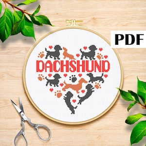 Könnte beinhalten: Ein Kreuzstichmuster in einem Holzrahmen zeigt ein Herzdesign mit Dackel-Silhouetten, Pfotenabdrücken und dem Wort "DACHSHUND" in Rot. Der PDF-Text ist oben rechts sichtbar.