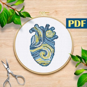 Könnte beinhalten: Kreuzstichmuster eines blauen und gelben Herzens mit einem wirbelnden Design, das an ein berühmtes Gemälde erinnert. Das Muster wird in einem hölzernen Stickrahmen angezeigt.