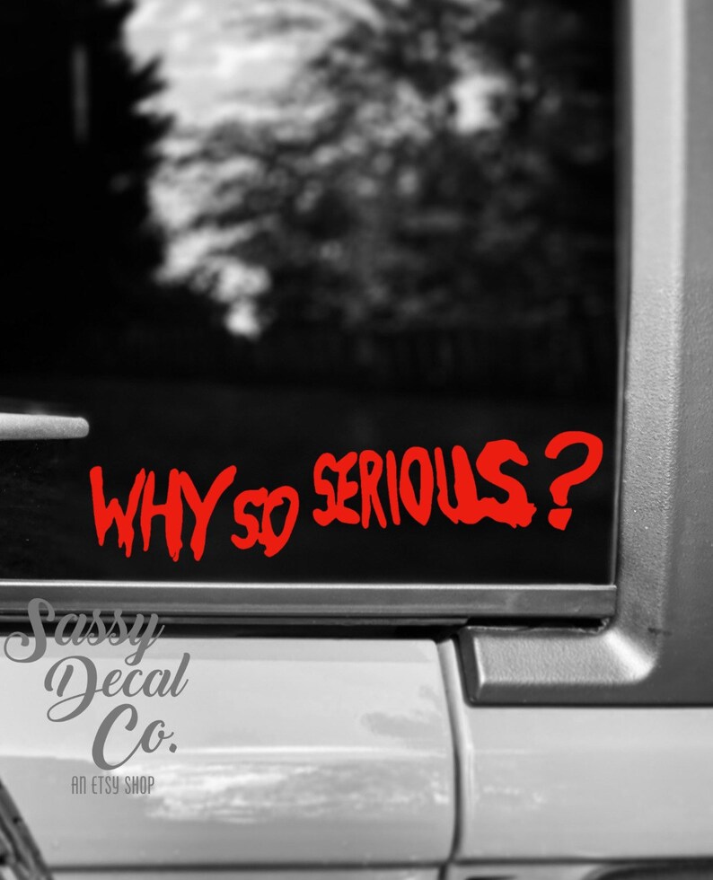 May include: A red vinyl decal with the text "WHY SO SERIOUS?" in a stylized font. The decal is on a black car window.