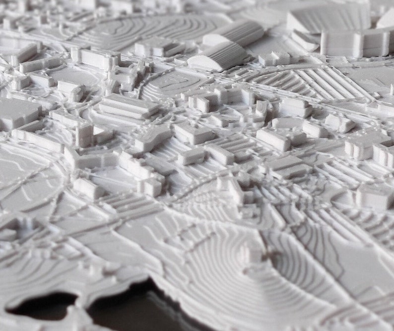 K&ouml;nnte beinhalten: Ein wei&szlig;es 3D-gedrucktes Modell einer Stadtlandschaft. Das Modell zeigt Geb&auml;ude, Stra&szlig;en und andere Details. Das Modell besteht aus glattem, wei&szlig;em Kunststoff.