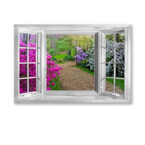 May include: A white window frame with a view of a garden path lined with purple and pink flowers. The path is made of wood chips and leads to a green grassy area.