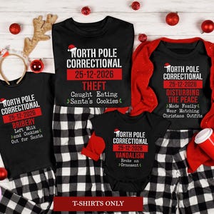 May include: A collection of black t-shirts and a baby bodysuit featuring the text North Pole Correctional 25-12-2026. Each garment displays a unique crime such as Theft, Bribery, Disturbing the Peace, or Vandalism with a small Santa hat icon.