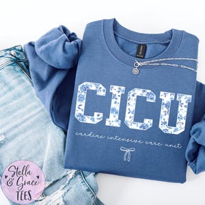 May include: A blue sweatshirt with the text "CICU cardiac intensive care unit" in white with a floral pattern. The text is in a collegiate font.