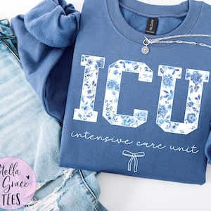 Peut inclure: Un sweat-shirt bleu avec un motif floral blanc qui dit "ICU Intensive Care Unit".