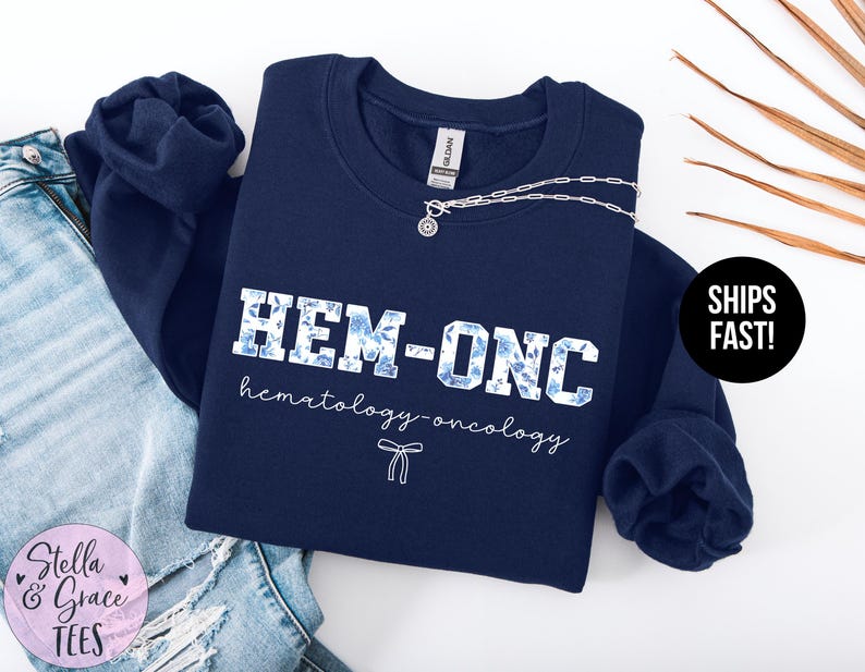 May include: Navy blue sweatshirt with a white floral design and the text "HEM-ONC hematology-oncology".