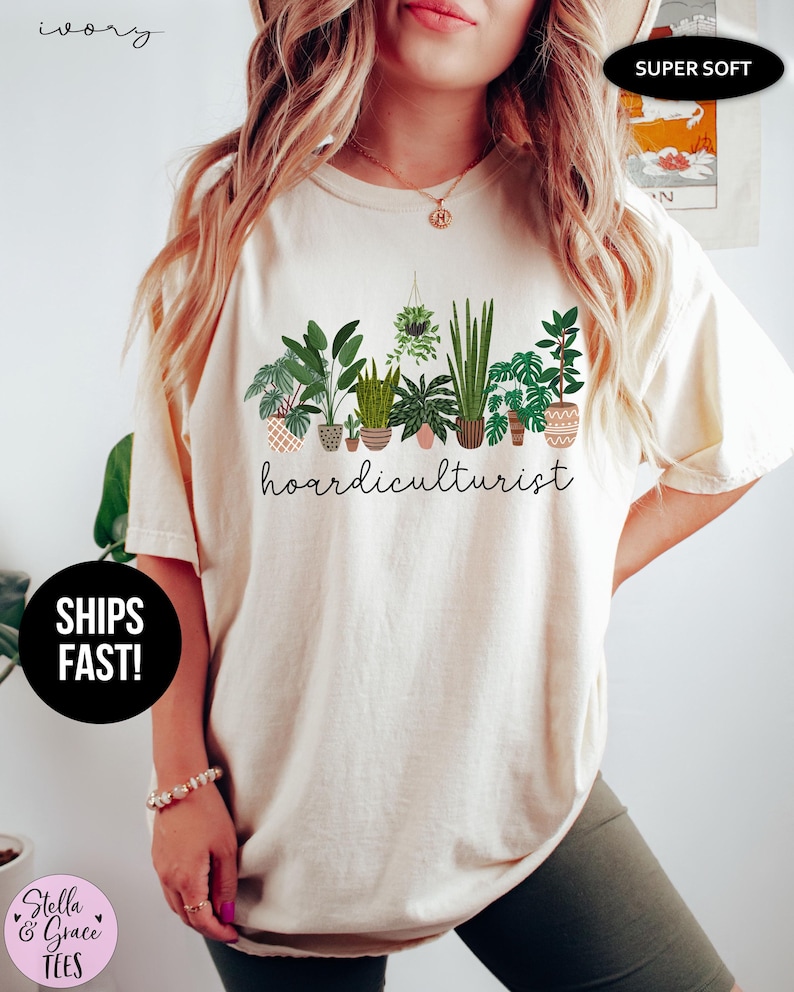 Op de afbeelding: Ivoor kleurig T-shirt met een afbeelding van verschillende potplanten en het woord "hoardiculturist". Het shirt is voorzien van de labels "Super Soft" en "Snel verzonden!"