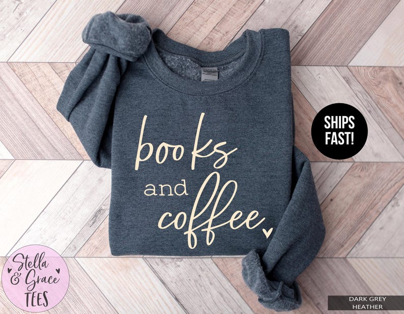 May include: Dark grey heather sweatshirt with the words "books and coffee" in a cream-colored script. The sweatshirt has a crew neck and long sleeves. The text "SHIPS FAST!" is in a black circle.