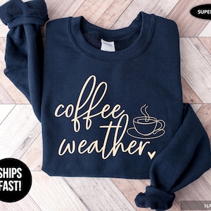 May include: Navy blue sweatshirt with the words "coffee weather" in a cursive font, along with a coffee cup graphic. The sweatshirt is labeled "super soft" and "navy".