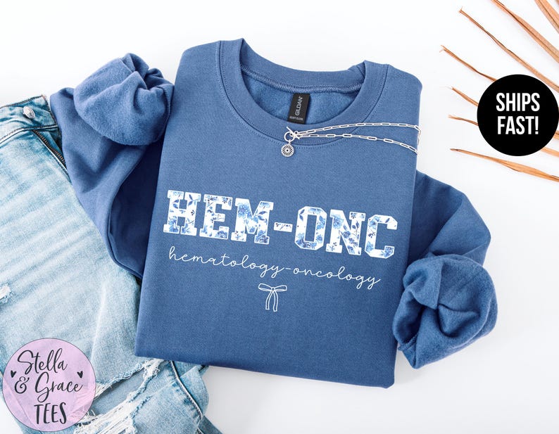 May include: A blue sweatshirt with the text "HEM-ONC hematology-oncology" in white with a floral pattern.