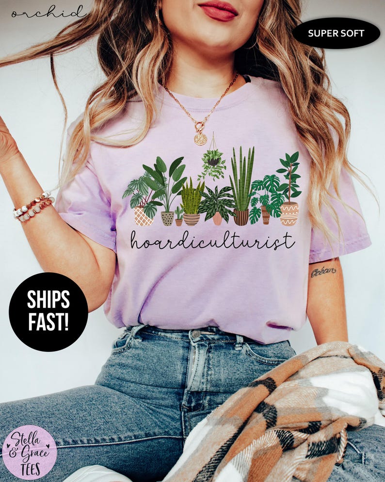 Op de afbeelding: Lichtpaars T-shirt met een afbeelding van verschillende potplanten en het woord "hoardiculturist" in script. Het shirt heeft ook de woorden "Super Soft" en "Ships Fast!"