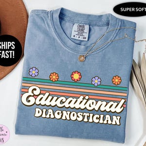May include: A blue t-shirt featuring the text "Educational Diagnostician" in a retro style, with colourful stripes and flower designs. The shirt has a crew neck and is made of soft material.