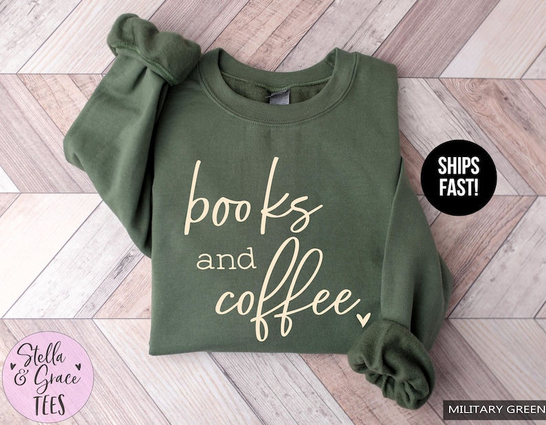 May include: Military green sweatshirt with the words "books and coffee" in a cursive font. The sweatshirt has a crew neck and long sleeves. The brand name "Stella & Grace Tees" is in a pink circle.