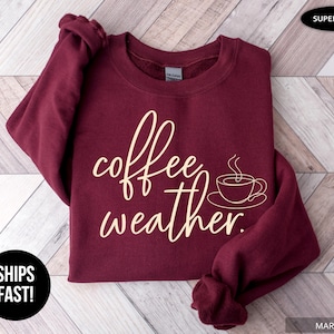 May include: Maroon crewneck sweatshirt with the words "coffee weather" in a cursive font and a coffee cup graphic. The sweatshirt is labeled "Super Soft".