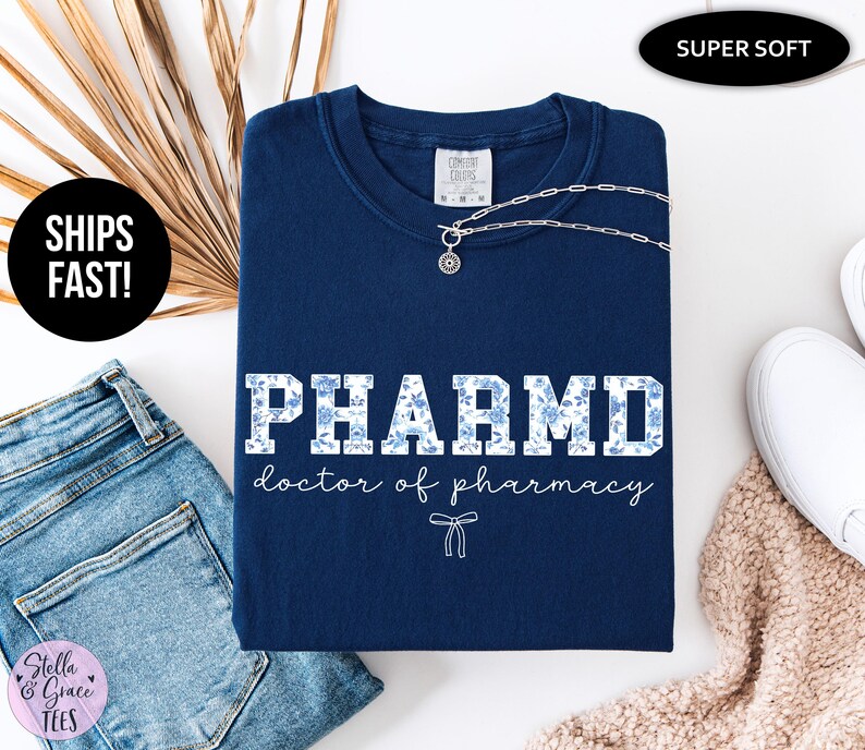 Puede incluir: Camiseta azul marino con un dise&ntilde;o de estampado floral blanco que dice "PHARMD doctor of pharmacy".