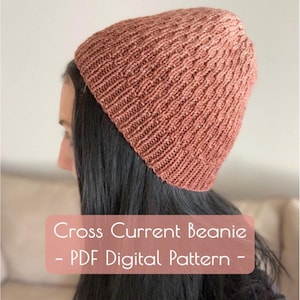 May include: A knitted beanie in a warm, earthy tone, possibly terracotta or rust, with a textured, ribbed pattern. The hat is shown on a person's head, with the text "Cross Current Beanie - PDF Digital Pattern -" overlaid on the image.
