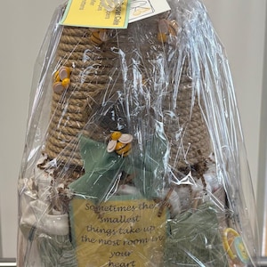 May include: A Winnie the Pooh themed diaper cake, wrapped in clear cellophane. The cake features a beehive design, decorative bees, and a sign with a quote. The base has a Winnie the Pooh graphic.