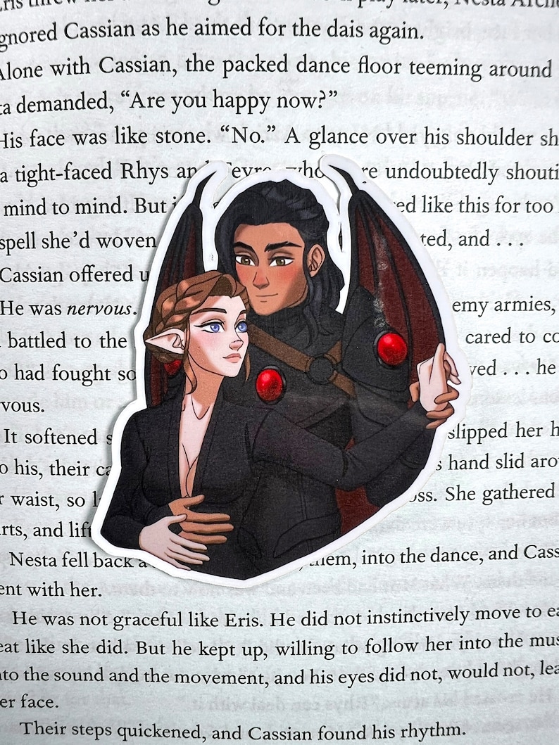 Puede incluir: Una pegatina con una ilustraci&oacute;n digital de una pareja bailando. La mujer tiene el pelo largo y casta&ntilde;o, ojos azules y lleva un vestido negro. El hombre tiene el pelo negro, ojos marrones y lleva una camisa negra y una capa roja. El fondo es una p&aacute;gina blanca con texto.