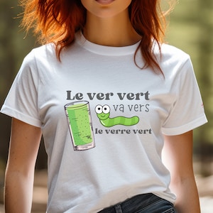 Puede incluir: Camiseta blanca con un gusano verde y un vaso de l&iacute;quido verde. El texto en la camiseta dice "Le ver vert va vers le verre vert".