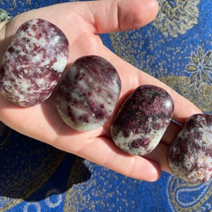 May include: Four tumbled stones with a white and pink marbled pattern. The stones are smooth and polished.