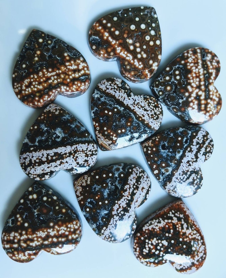 May include: Eight heart-shaped polished stones with a brown and white speckled pattern.