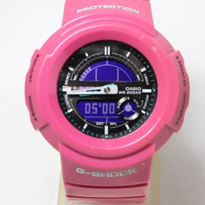 Puede incluir: Un reloj Casio G-Shock rosa con una esfera negra y una pantalla digital. El reloj tiene un acento azul y verde alrededor de la esfera y las palabras "CASIO WR 20BAR" impresas en la esfera.