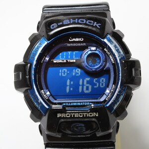 May include: Black and blue G-Shock digital watch with a blue digital display showing the time. The watch has multiple buttons and text including "G-SHOCK", "CASIO", and "WR20BAR". The watch face displays "10-19" and "1:16:58".