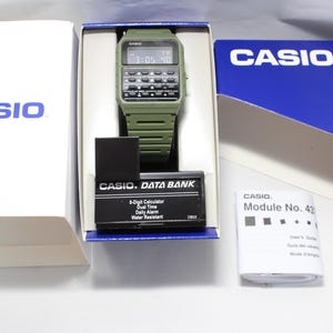 May include: A green Casio Data Bank watch with a digital display and a calculator function. The watch has a black band and a white face with the text "CASIO. DATA BANK" and "8-Digit Calculator, Dual Time, Daily Alarm, Water Resistant".