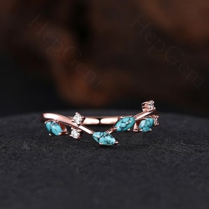 May include: A delicate rose gold ring with a vine design featuring turquoise and clear stones.