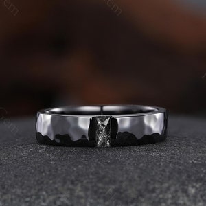 May include: A black hammered band with a single black diamond set in a square shape.
